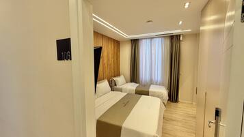 Une chambre d’hôtel avec deux lits, un mur décoratif en bois, une grande fenêtre avec des rideaux et une porte dotée d’une poignée moderne.