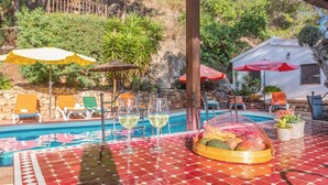 A poolside table with a red patterned tablecloth, two wine glasses, and a fruit basket. - Casa Surrender Cómpeta by Ruralidays (Málaga)