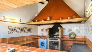 Une cuisine compacte équipée d’un four encastré, d’un lave-linge et d’une étagère où sont rangés des bocaux.