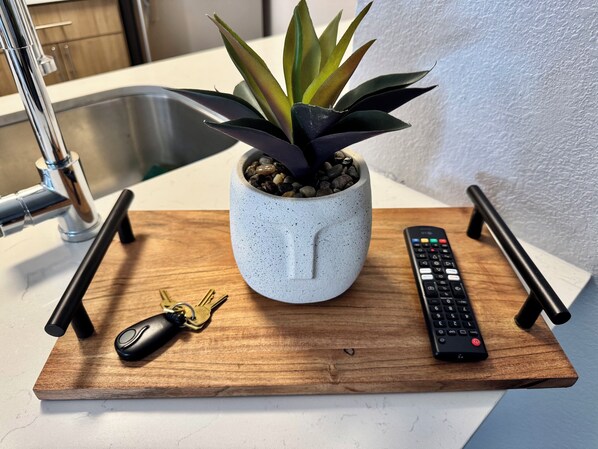 Un comptoir de cuisine avec une plante en pot, une télécommande et un trousseau de clés, le tout posé sur un plateau en bois.