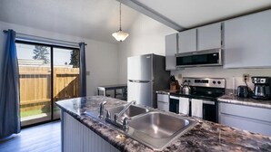 A modern kitchen with a granite countertop, stainless steel sink, and built-in appliances including a refrigerator, microwave, and stove.