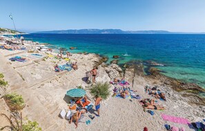 A beach with people sunbathing and swimming, clear blue water, and rocky terrain. - Lovely home in Labin with outdoor swimming pool (Labin)