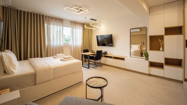 Una camera d'albergo moderna con un letto, una scrivania, una TV e un grande specchio.