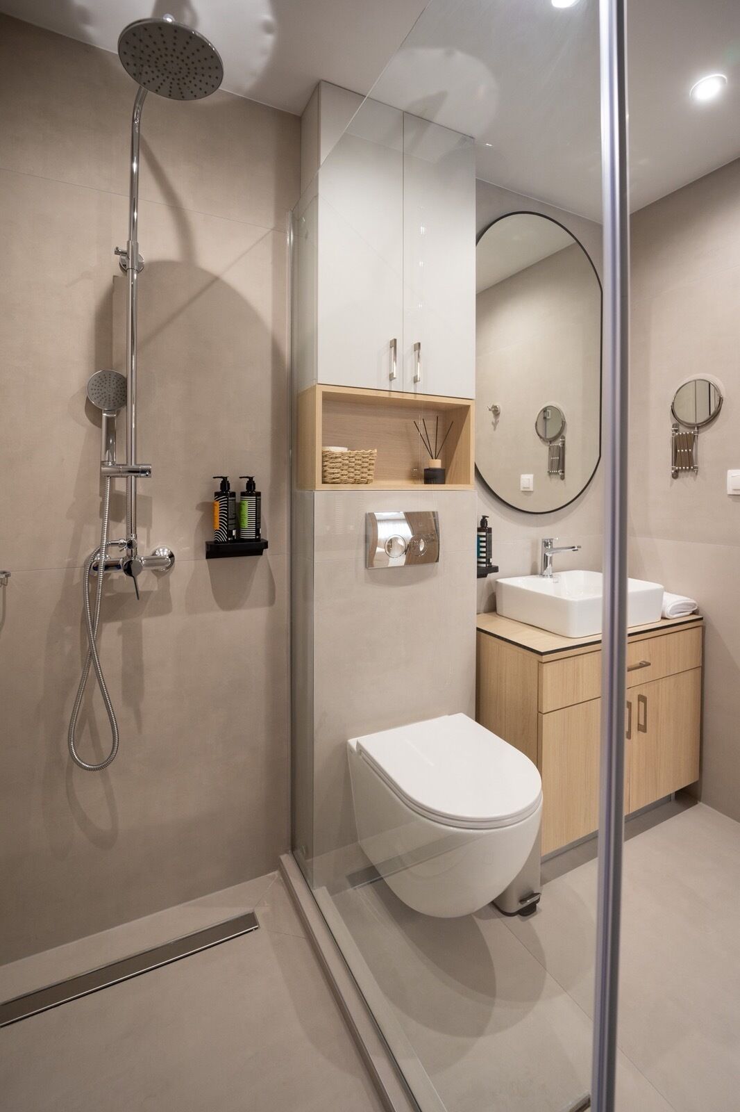 A modern bathroom with a glass-enclosed shower, a white toilet, a sink, and a mirror.