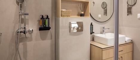 A modern bathroom with a glass-enclosed shower, a white toilet, a sink, and a mirror.