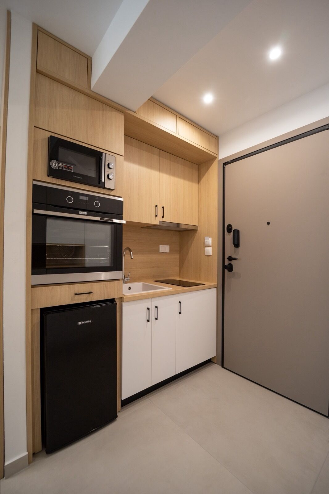 A compact kitchen with built-in appliances, a sink, and a door.