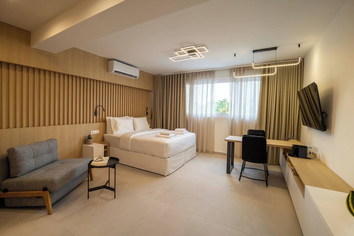 Una habitación de hotel moderna con una cama, un escritorio, un sofá y un televisor.