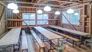 A rustic wooden interior with long benches and hanging pendant lights.