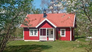 A red house with a white porch and a chimney.