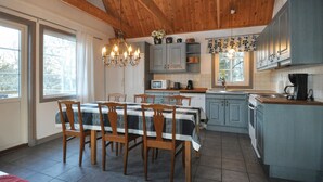 A kitchen with wooden cabinets, a dining table with chairs, and a chandelier.