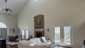 A spacious living room with a fireplace, a dining area, and a large window. - Enjoy Derby City in this amazing river bungalow! (Louisville)