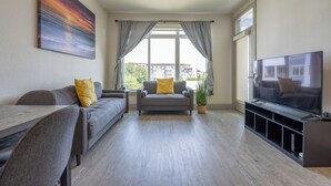 A modern living room with a grey sofa, a TV, and a dining table.