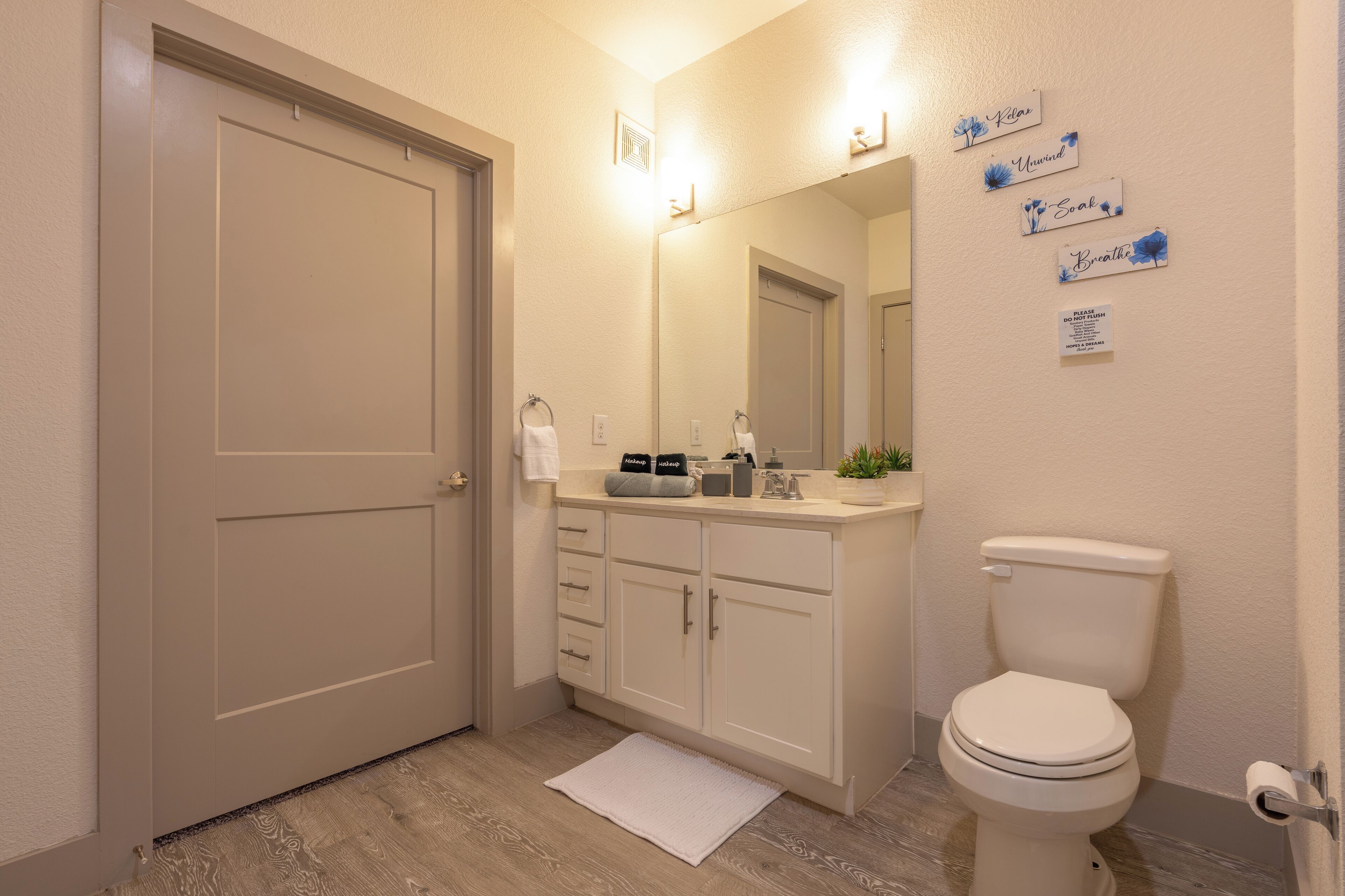Een badkamer met toilet, wastafel en kast. Er zijn wandlampen en een spiegel.