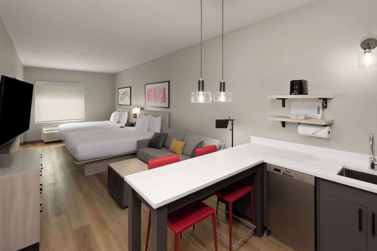 Una habitación de hotel moderna con cama, sofá, zona de comedor y cocina.