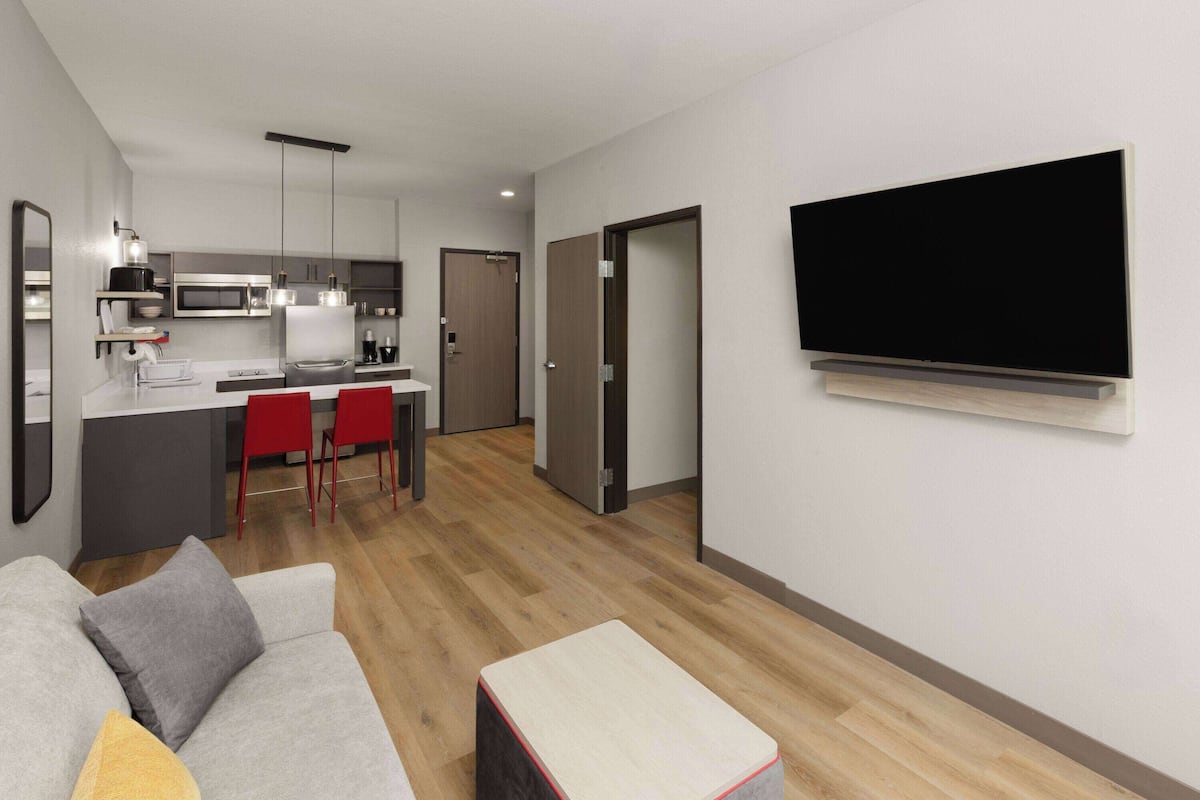 Una sala de estar moderna con un sofá gris, una mesita de centro y un televisor de pantalla plana montado en la pared.