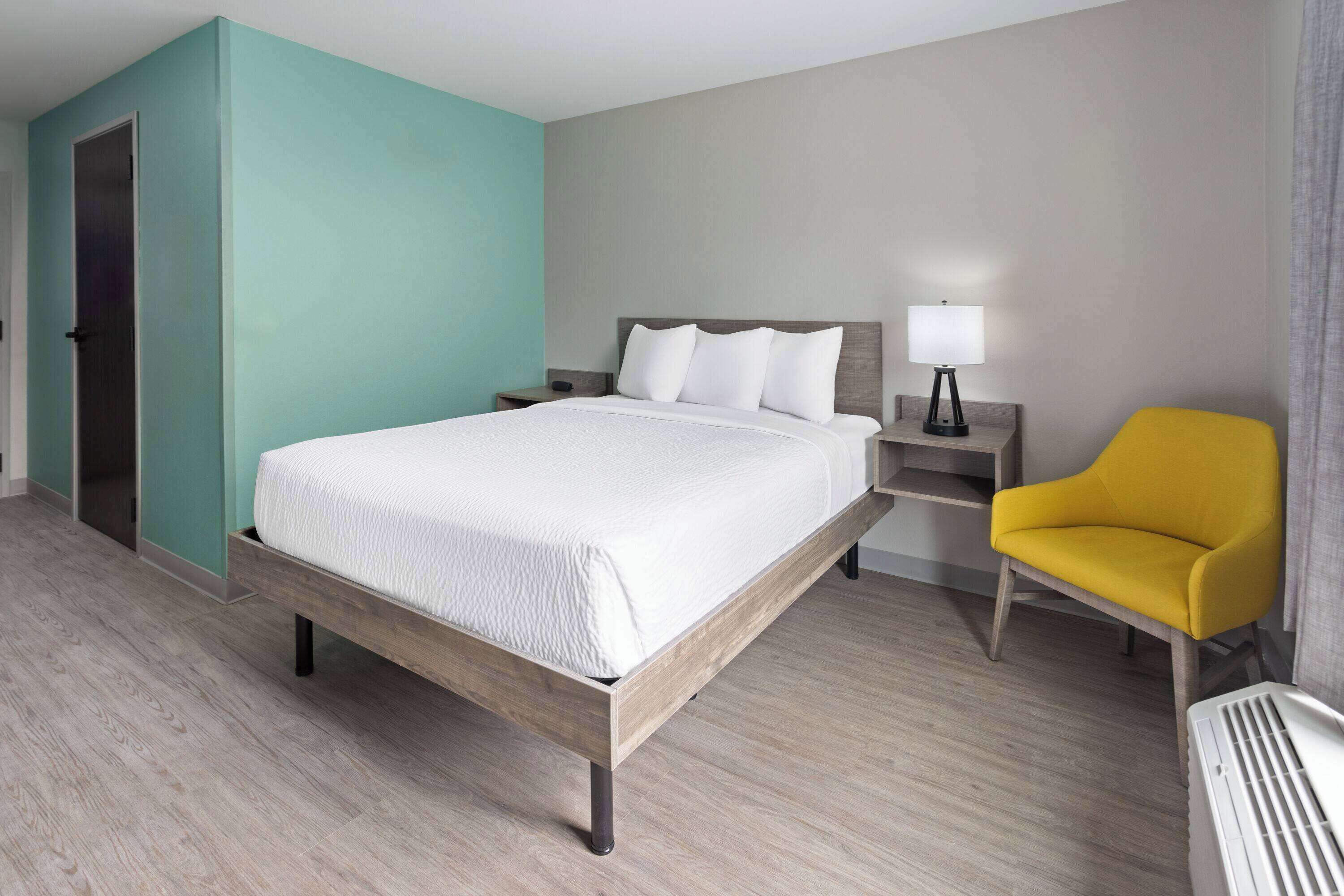 Une chambre d’hôtel avec un lit, une table de chevet, une lampe et une chaise.
