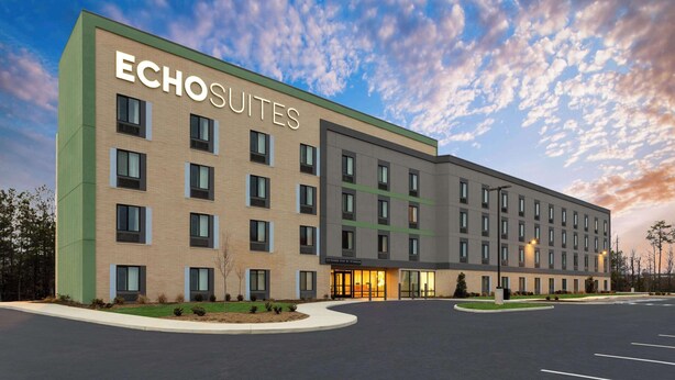 En modern hotellbyggnad som heter ”Echosuites” och har en fasad av tegel, många fönster och en väl upplyst entré.