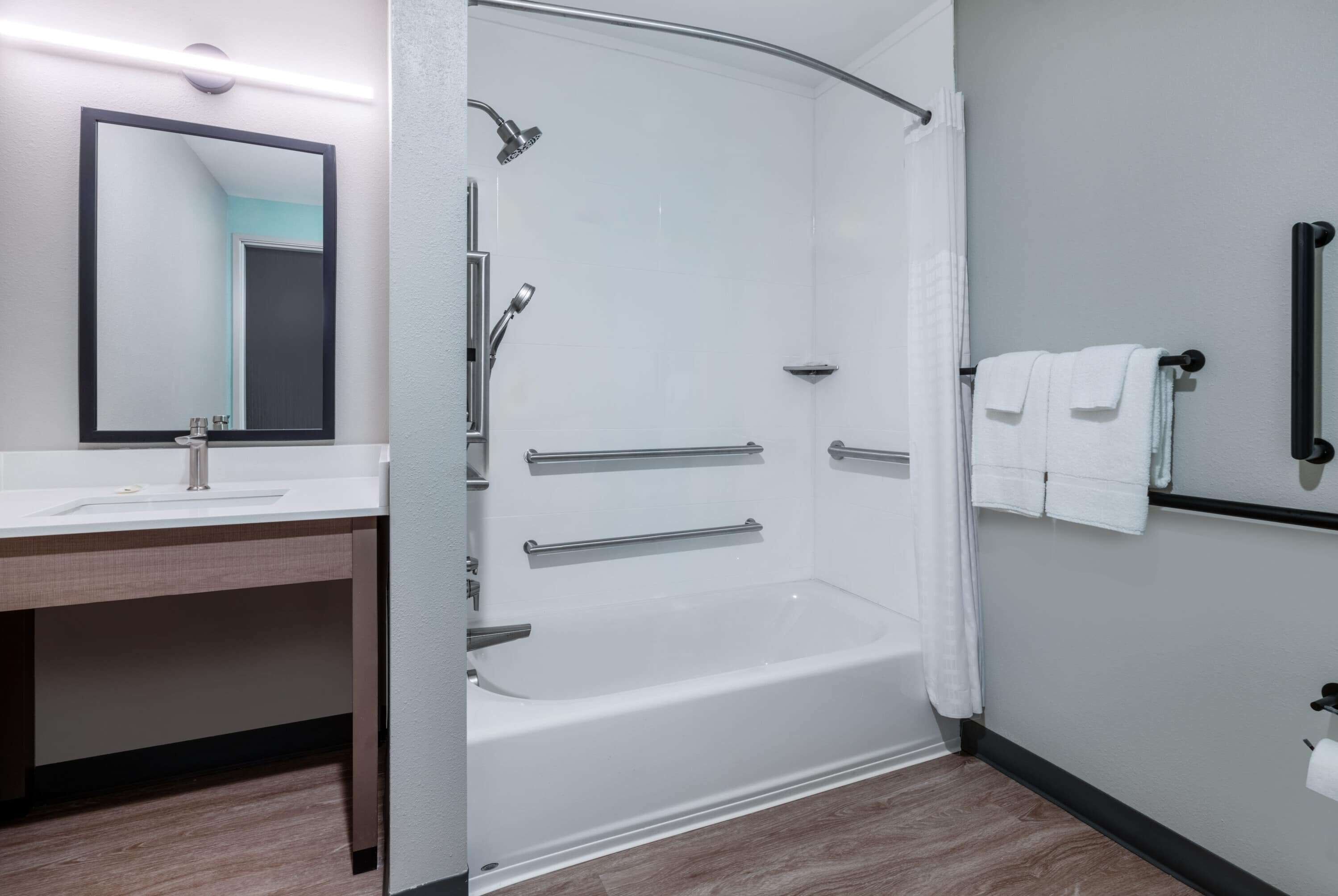Een moderne badkamer met een douche, wastafel en spiegel.