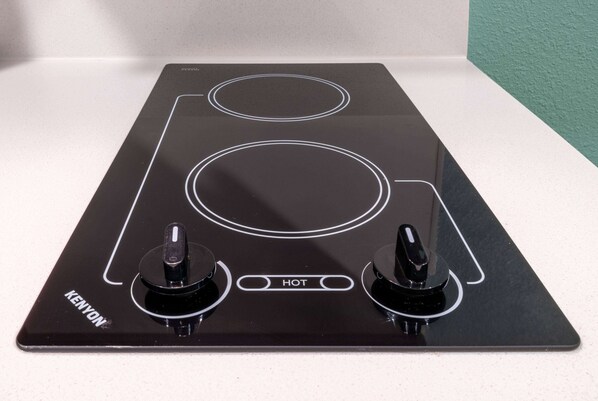 Une plaque de cuisson électrique Kenyon noire, dotée de deux brûleurs et d’un panneau de commande.