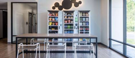 Una cocina moderna con una isla grande, sillas blancas y un refrigerador para bebidas lleno de aperitivos y refrescos.