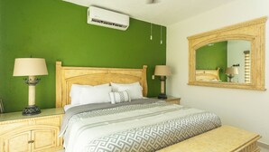 A bedroom with a bed, bedside tables, a bench, a mirror, and an air conditioning unit. - Casa 25 Lizette Luxury for 6-7 px with Pool Cancun! (Cancún)