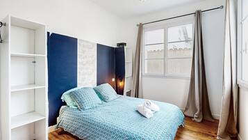 Een slaapkamer met een bed, een kledingkast, een raam en gordijnen.