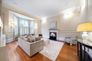 A living room with a sofa, a fireplace, a television, and a lamp.
