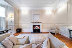 Un salon avec une cheminée, un ensemble de canapés et un téléviseur.