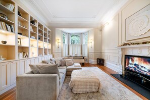 Un soggiorno con un divano beige, un camino e una libreria piena di libri e oggetti decorativi.