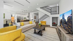 A modern living room with a sofa, yellow armchairs, a coffee table, and a cityscape painting.