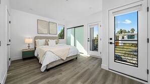 A bedroom with a bed, nightstands, a window, and a sliding door to a balcony.