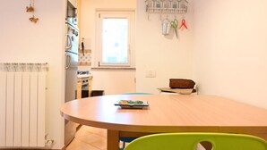 Et køkken med et hvidt køleskab, et vindue og et spisebord med stole.