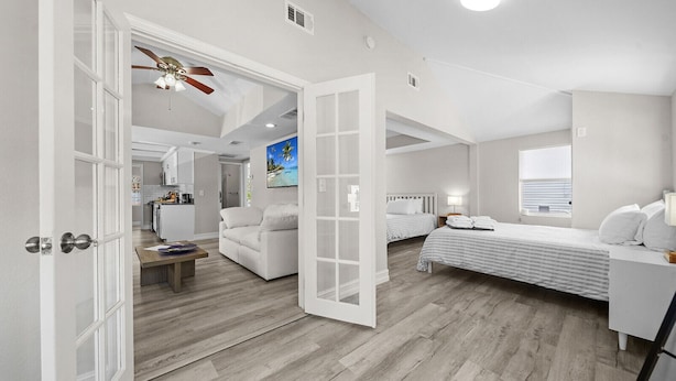 A spacious room with a large bed, a smaller bed, a sofa, and a dining area.