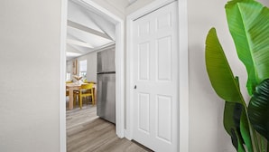 A hallway with a white door leading to a kitchen area.
