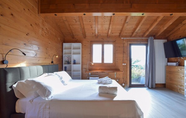 Quarto acolhedor de cabana de madeira com cama, escrivaninha e televisão.