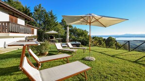 Un patio con sillones de descanso y un jacuzzi, con vista a un lago.