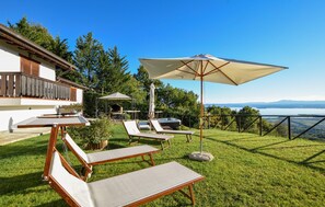 Une terrasse avec des chaises longues et un jacuzzi, donnant sur un lac.