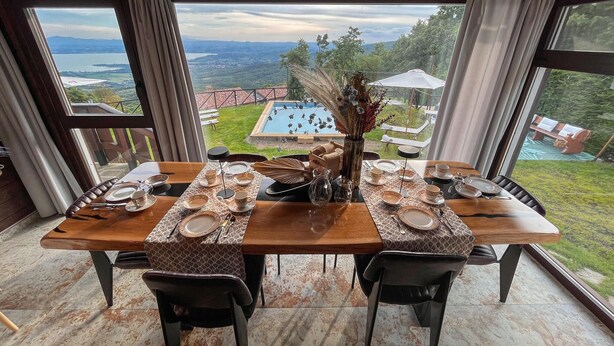 Mesa de comedor para cuatro con vista a una piscina y paisaje.