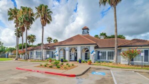 A building with a tiled roof, a wheelchair-accessible entrance, and palm trees.