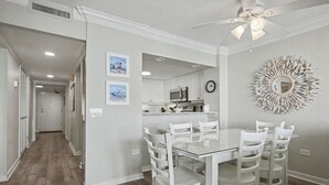 A modern kitchen with white cabinets, a microwave, and a dining area with a glass table and white chairs. -  Discount option!! Beautiful views! 3BR/3BA Oceanfront condo Ocean Creek Resort! (Myrtle Beach)
