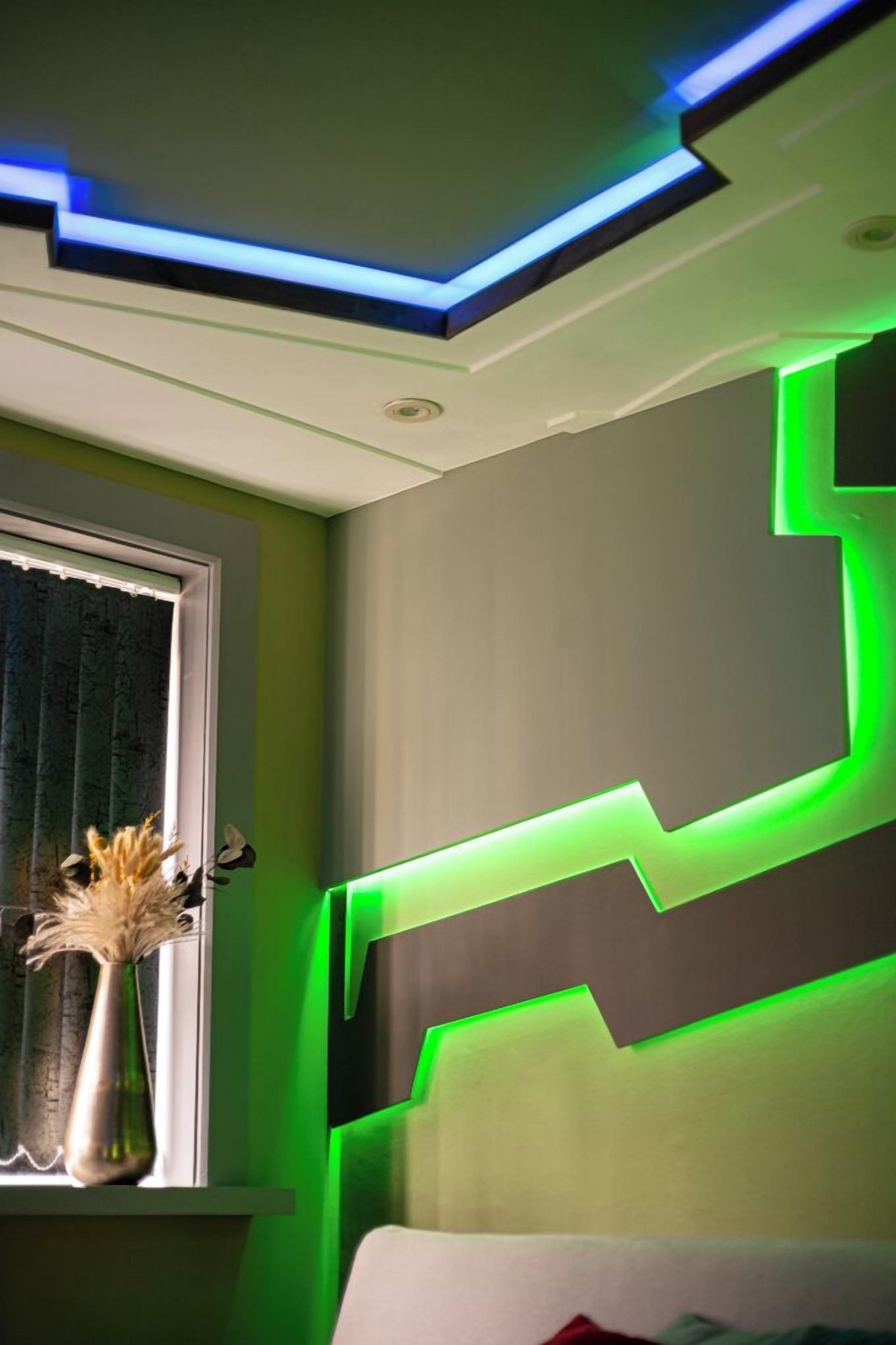Una stanza con un moderno design del soffitto e illuminazione blu e verde.