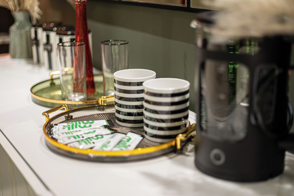 A tray with stacked cups and a coffee maker on a countertop.