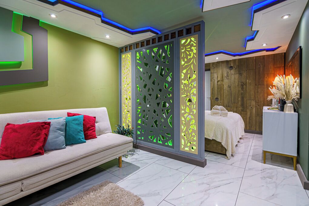 Un espace de spa moderne avec un canapé blanc, un élément de séparation décoratif et une table de massage.