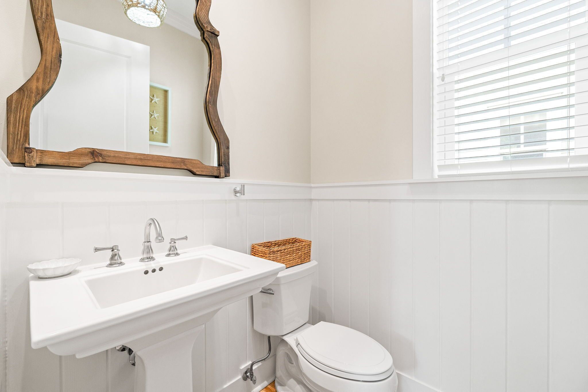 Een badkamer met een wit wastafel, toilet en een spiegel met houten lijst.