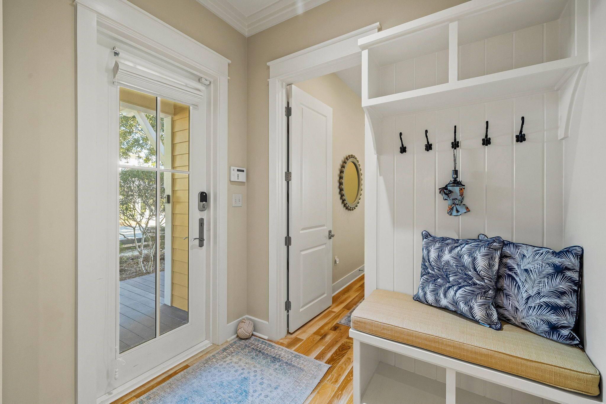 A hallway with a bench, a coat rack, and a door leading outside.