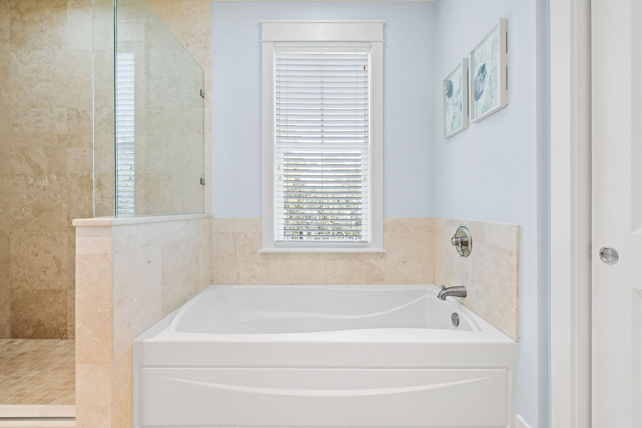 A bathroom with a bathtub, a shower, and a window with blinds.