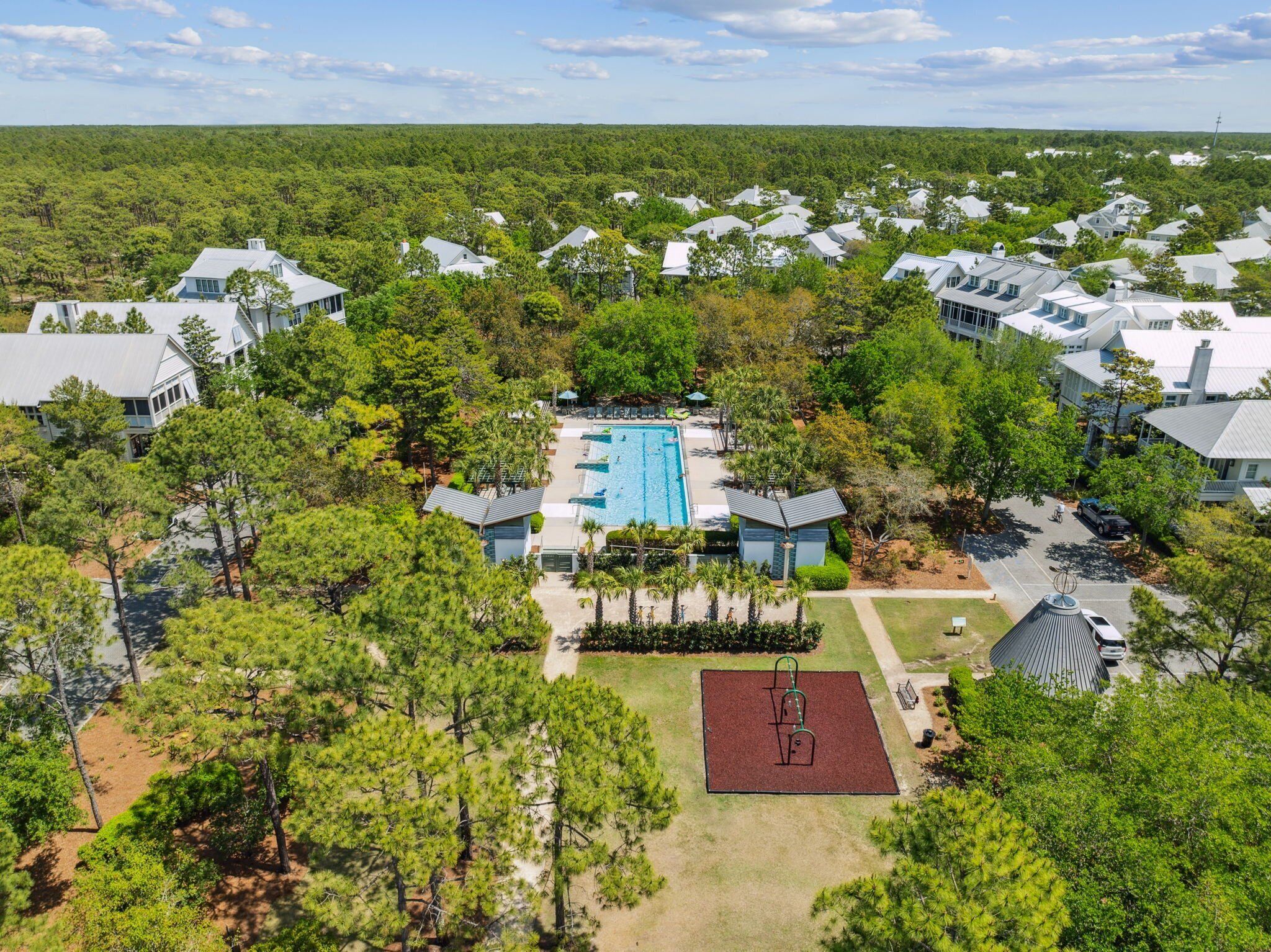An aerial view of a residential area with a swimming pool surrounded by houses and trees.