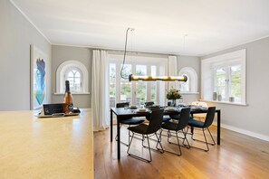 Un espace repas avec une table en bois, des chaises noires et un luminaire suspendu moderne.