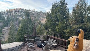 A deck with outdoor seating and a bear statue.