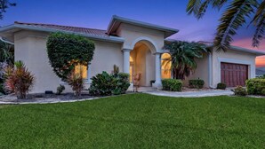 A two-story house with a well-maintained lawn, a large archway entrance, and a garage. - Luxe Escape in The Forest Country Club - South Fort Myers (Fort Myers)
